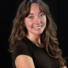 A smiling young woman with a brown shirt