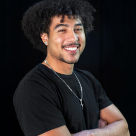 A smiling young man wearing a black t-shirt