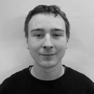 A black and white headshot of a young man with short curly hair